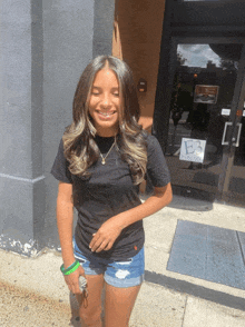 a girl in shorts and a black shirt stands in front of a building with a sign that says b3 on it