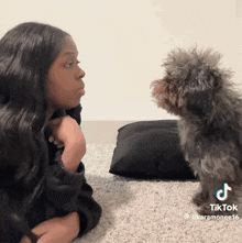 a tiktok video of a woman talking to a small black dog