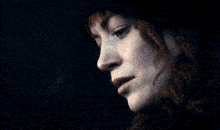 a close up of a woman 's face with a dark background and a watermark that starts with the letter r