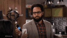 a man in a suit and plaid shirt is holding a cell phone in his hand .