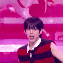 a young man is standing on a stage wearing a red and black striped shirt and tie .