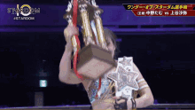 a female wrestler holds a trophy in front of a sign that says stardom