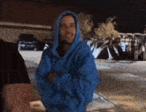 a man wearing a blue hoodie is standing in front of a building .