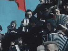 a group of men are playing accordions and a red flag is flying in the background