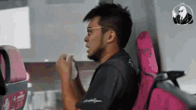 a man wearing glasses is sitting on a bus with a pink seat .