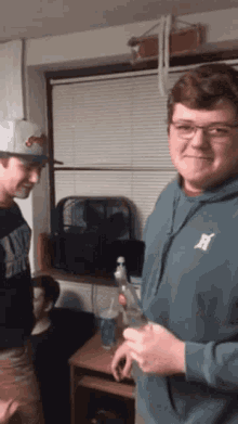 a man wearing a hoodie with the letter h on it stands next to another man