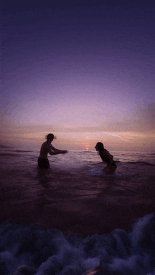 a man and a woman are in the ocean at sunset