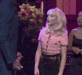a woman in a pink top and black skirt stands in front of a man