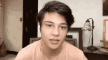 a young man wearing headphones and a pink shirt is sitting in front of a lamp in a living room .