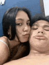 a woman is kissing a man on the cheek while making a funny face