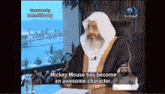 a man with a beard is sitting at a desk and talking about mickey mouse