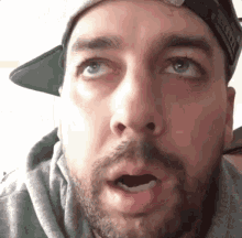 a man with a beard is wearing a hat and a hoodie