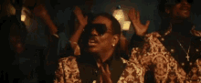 a man wearing sunglasses is standing in front of a crowd .