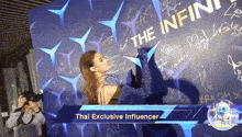 a woman standing in front of a wall that says the infini