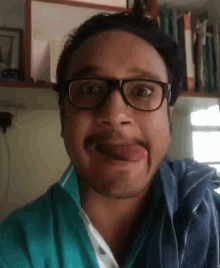 a man with glasses and a mustache is sticking out his tongue .