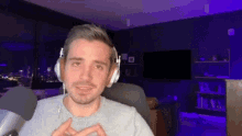 a man wearing headphones is making a heart shape with his hands while sitting in front of a microphone .