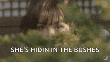 a woman is hiding behind a bush with the words she 's hiding in the bushes