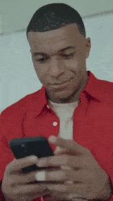 a man in a red shirt looks at his phone