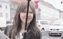 a woman is holding an umbrella and smiling while standing on a street .