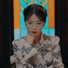 a woman wearing glasses and a striped shirt with butterflies on it .