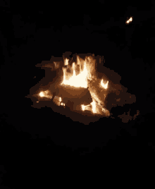 a fire is burning in the dark with sparks coming out of it .