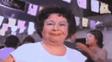 a woman in a white shirt is smiling in front of a crowd of people at a party .