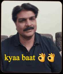 a man with a mustache is wearing a black shirt with the words kyaa baat written in yellow