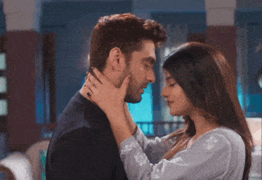 a woman is touching a man 's face while he looks at her