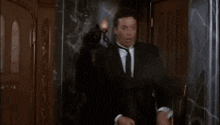 a man in a suit and tie is standing in front of a statue and says oh good shot green