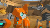 a couple of orange robots are standing next to each other in a desert .