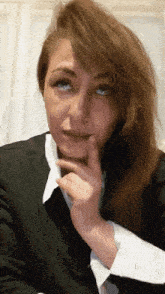 a woman in a black suit and white collared shirt is making a funny face