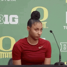 a woman is sitting at a table with a microphone in front of a green wall .