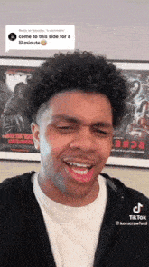 a man is making a funny face in front of a movie poster