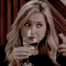 a woman is holding a glass of wine in her hand and drinking it .