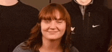 a woman with red hair is making a funny face in front of two men .