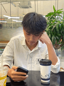 a man sitting at a table with a cup of coffee and a cell phone