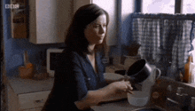 a woman washing dishes in a kitchen with bbc written on the bottom of the screen