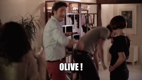 a group of people are standing in a room and the word olive is on the bottom