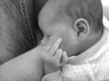 a black and white photo of a baby breastfeeding .