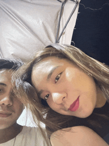 a man and a woman are posing for a picture and the woman is wearing red lipstick