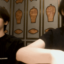 a man wearing a black balenciaga t-shirt stands next to another man