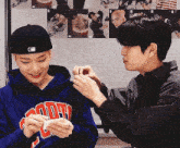 a man wearing a blue hoodie with the word hoody on it is being touched by another man