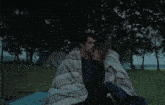 a man and woman wrapped in a blanket are kissing