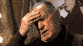 a man covering his face with his hand in front of a picture of elvis presley playing a guitar