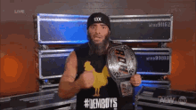 a man wearing a black hat with the number 13x on it is holding a wrestling belt