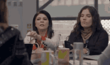 a group of women are sitting at a table with coffee cups .