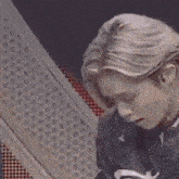 a close up of a person 's face with blonde hair and a black shirt .