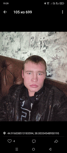 a man in a leather jacket is sitting on a couch with the number 105 in the upper left corner