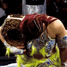 a woman with red hair is holding a gold wrestling belt