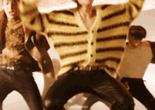 a man in a yellow and black striped sweater is dancing with other people